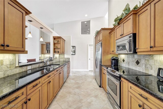 kitchen featuring light tile patterned floors, sink, dark stone countertops, decorative light fixtures, and stainless steel appliances