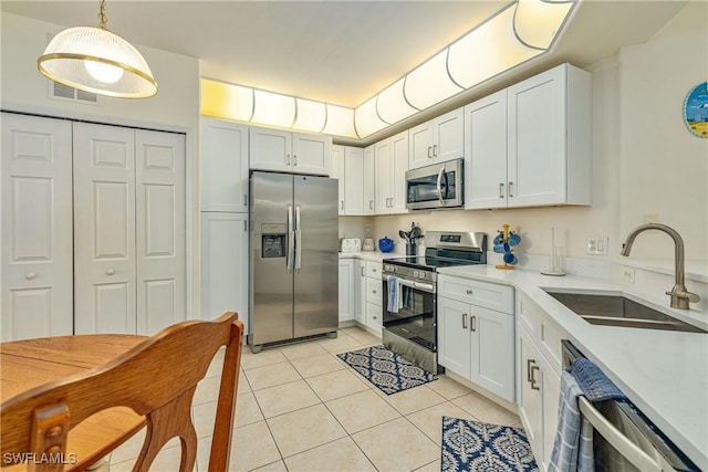 kitchen featuring hanging light fixtures, sink, white cabinets, and stainless steel appliances