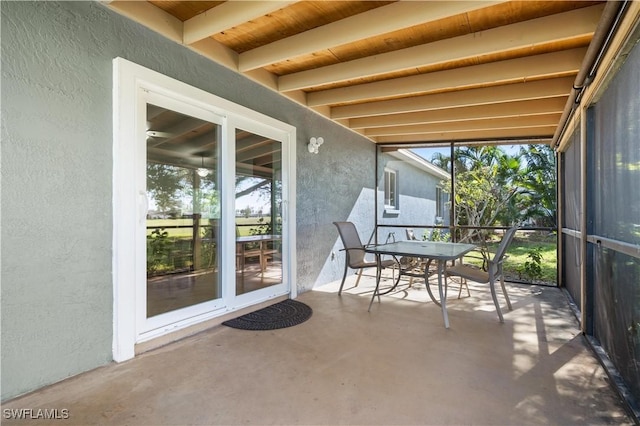 unfurnished sunroom featuring beamed ceiling, a wealth of natural light, and wooden ceiling