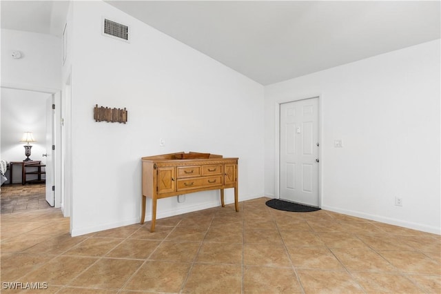 spare room featuring lofted ceiling and light tile patterned flooring