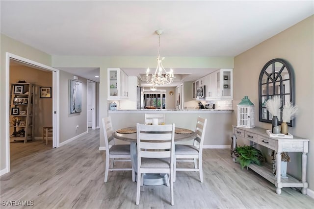 dining space featuring an inviting chandelier and light hardwood / wood-style flooring