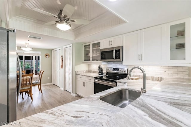 kitchen featuring sink, white cabinetry, stainless steel appliances, and a tray ceiling