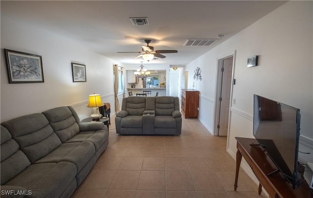 tiled living room featuring ceiling fan with notable chandelier