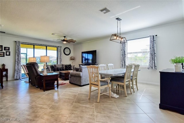 tiled dining area featuring a wealth of natural light, crown molding, ceiling fan, and a textured ceiling