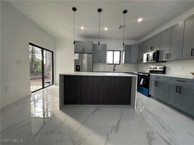 kitchen with a center island, backsplash, hanging light fixtures, gray cabinets, and appliances with stainless steel finishes