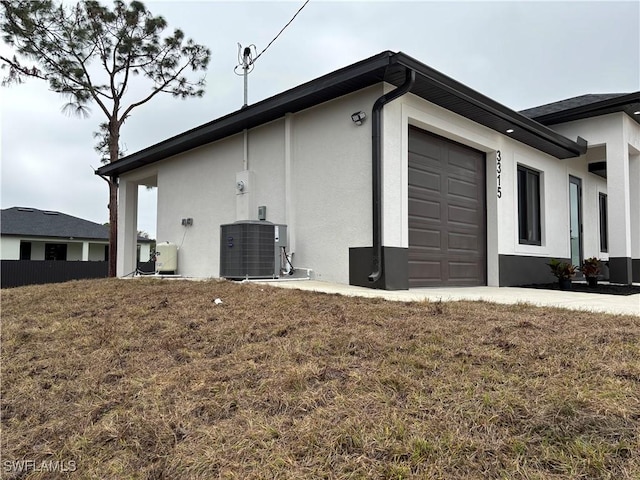 view of side of property with central air condition unit, a lawn, and a garage