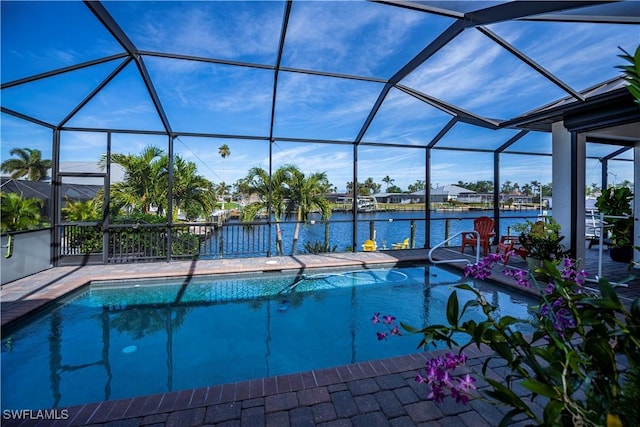 view of pool featuring glass enclosure, a water view, and a patio