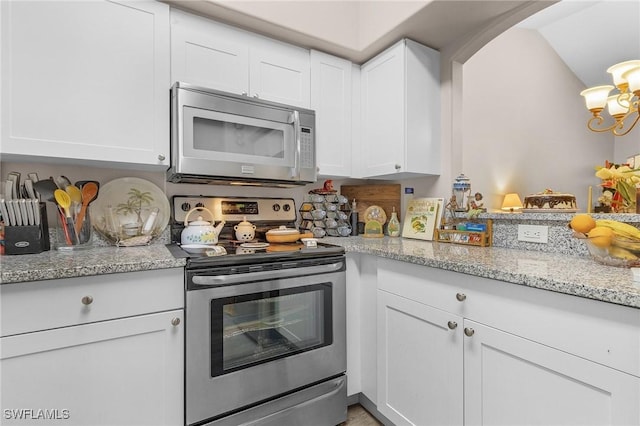 kitchen featuring white cabinets, light stone counters, and electric stove