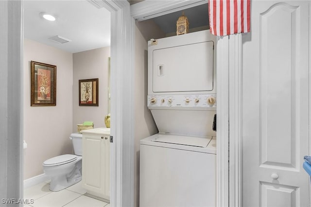 laundry area with light tile patterned flooring and stacked washer and clothes dryer