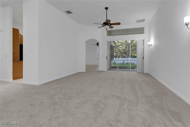 interior space with a high ceiling, light colored carpet, and ceiling fan