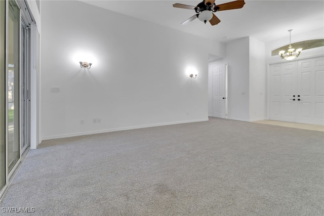 unfurnished room featuring ceiling fan with notable chandelier and light carpet