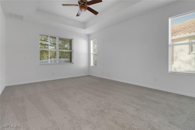 carpeted empty room featuring a tray ceiling and ceiling fan