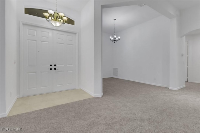 carpeted foyer entrance with beam ceiling and a chandelier