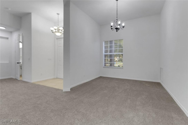 spare room featuring light colored carpet and an inviting chandelier