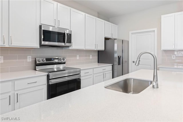 kitchen with decorative backsplash, stainless steel appliances, white cabinetry, and sink