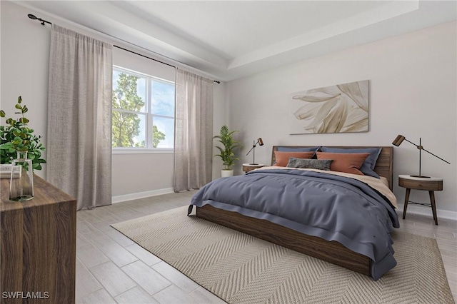 bedroom with light hardwood / wood-style floors and a raised ceiling