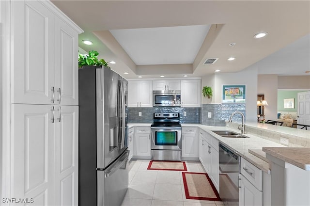 kitchen with white cabinets, a raised ceiling, sink, light tile patterned flooring, and stainless steel appliances