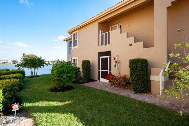 back of property with a lawn and a water view