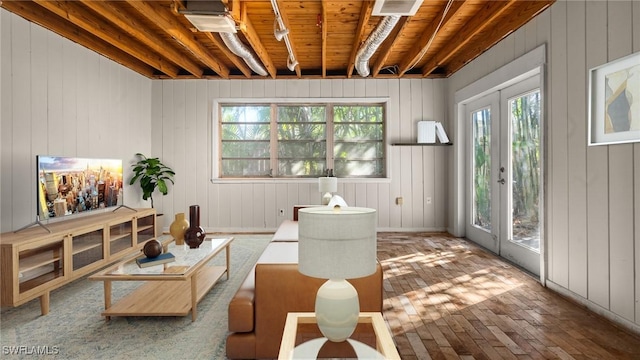 interior space featuring french doors, beam ceiling, wooden walls, and wood-type flooring