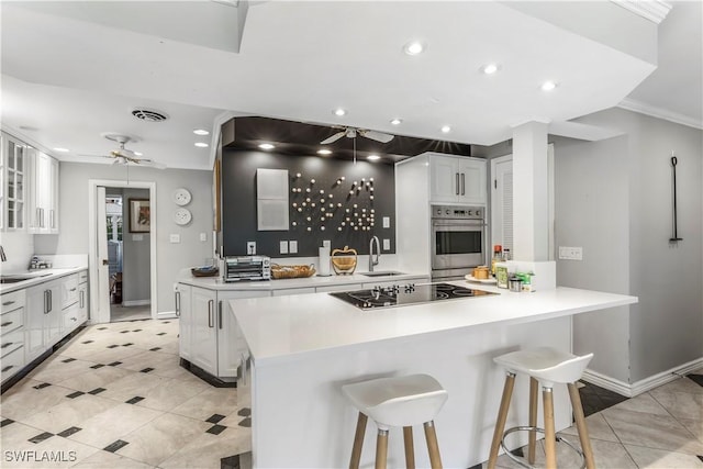 kitchen with white cabinets, oven, a kitchen bar, and sink