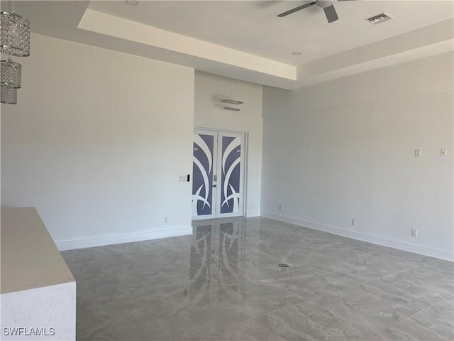 spare room featuring french doors, a tray ceiling, and ceiling fan