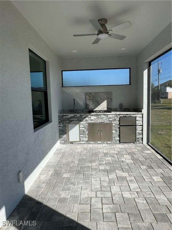 view of patio with ceiling fan, sink, and an outdoor kitchen