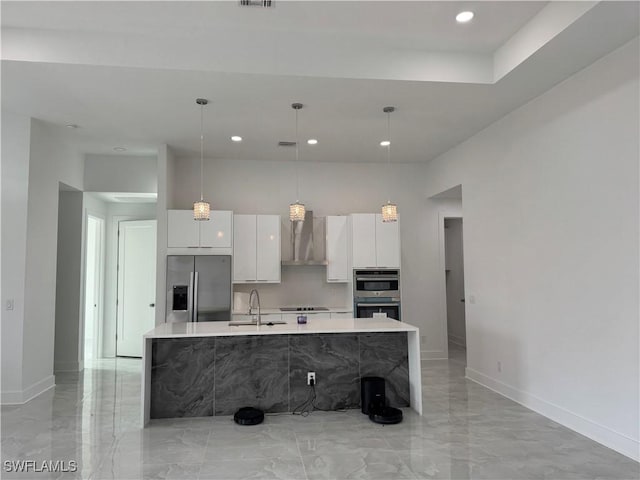 kitchen with appliances with stainless steel finishes, wall chimney exhaust hood, a kitchen island with sink, sink, and white cabinets