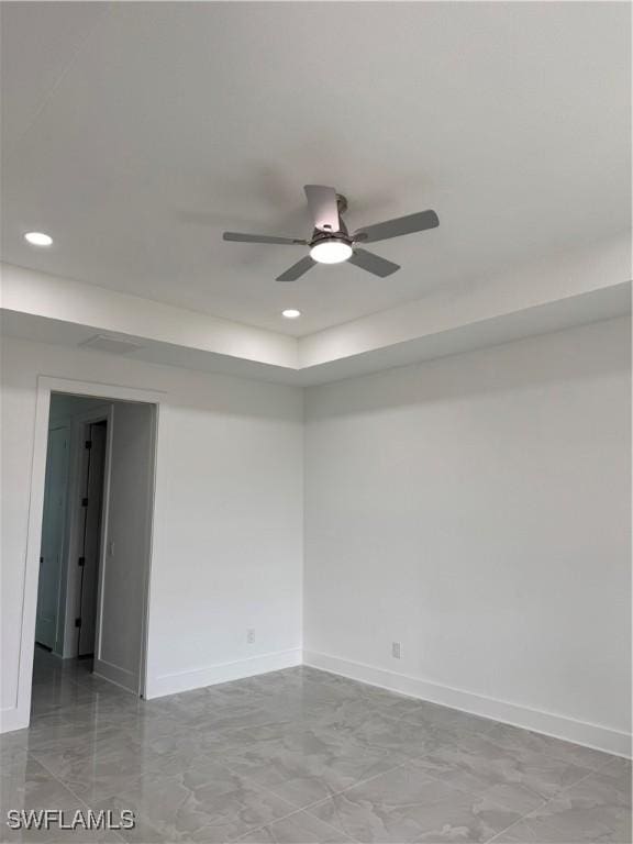 empty room with a raised ceiling and ceiling fan