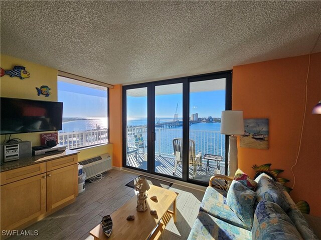 living room featuring a textured ceiling, wood-type flooring, a healthy amount of sunlight, and a water view