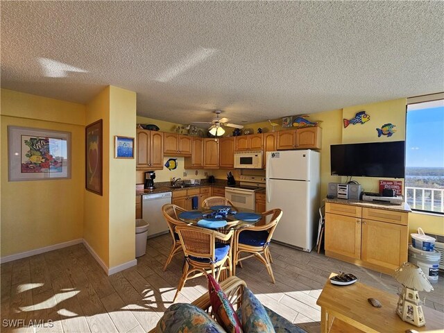 dining space with ceiling fan, sink, light hardwood / wood-style flooring, and a textured ceiling