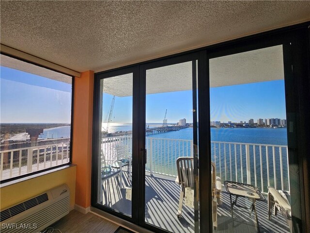 sunroom / solarium featuring a wall mounted air conditioner and a water view