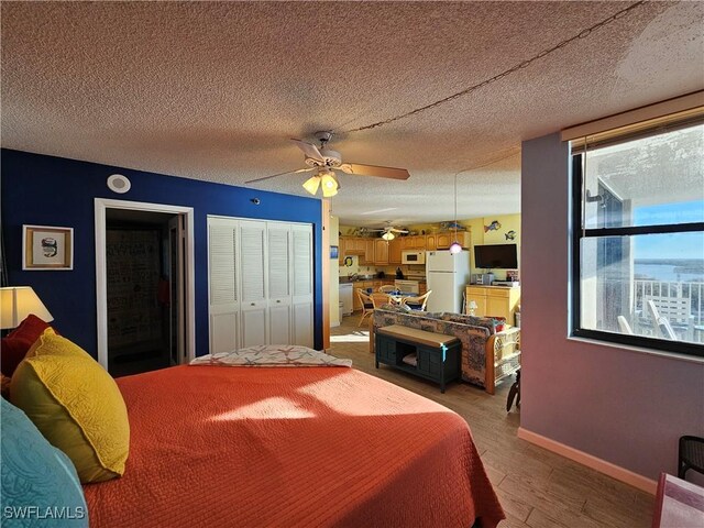 bedroom with ceiling fan, hardwood / wood-style floors, white fridge, and a textured ceiling