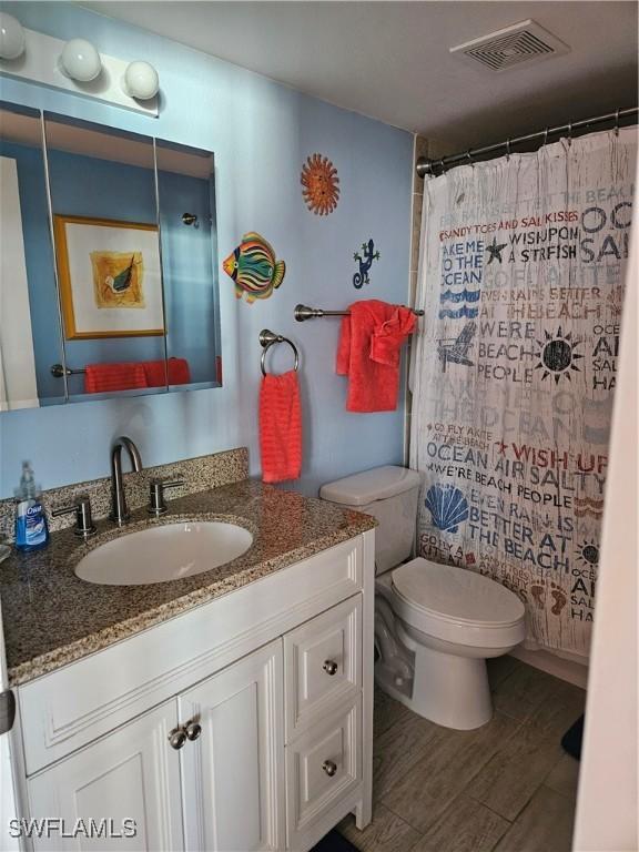 bathroom featuring hardwood / wood-style flooring, vanity, toilet, and walk in shower