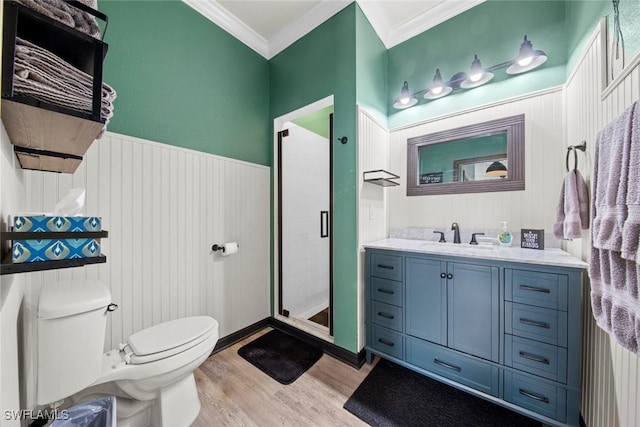 bathroom featuring crown molding, wood-type flooring, toilet, a shower with door, and vanity