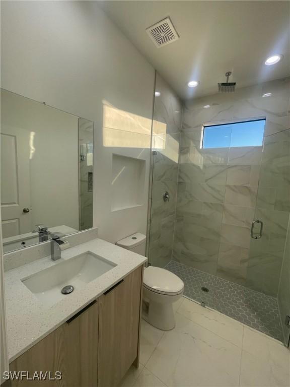 bathroom with vanity, toilet, and a shower with shower door