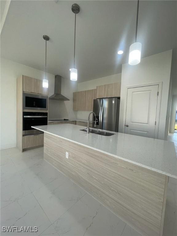 kitchen with decorative light fixtures, sink, wall chimney range hood, and stainless steel appliances