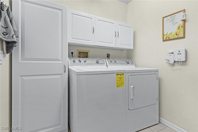 laundry area with washer and dryer, light tile patterned flooring, and cabinets