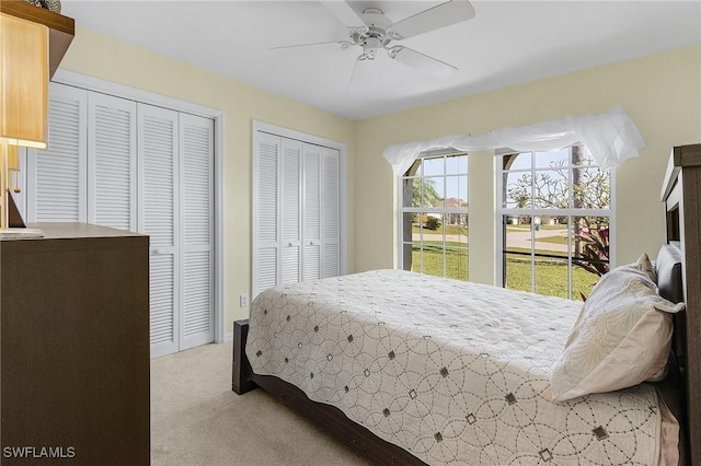 carpeted bedroom featuring multiple closets and ceiling fan