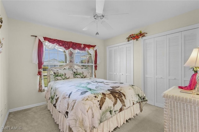 bedroom featuring ceiling fan, light carpet, and two closets