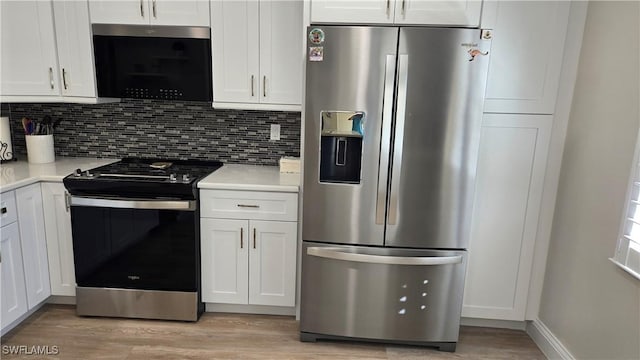 kitchen featuring light hardwood / wood-style floors, backsplash, white cabinets, and stainless steel appliances