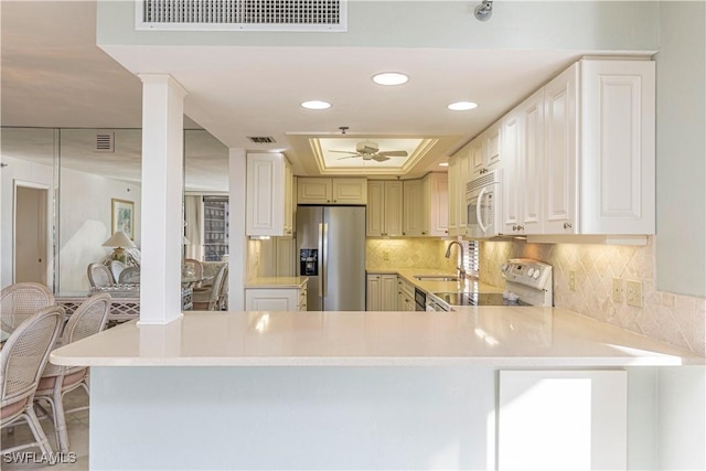 kitchen with kitchen peninsula, white appliances, ceiling fan, sink, and white cabinets