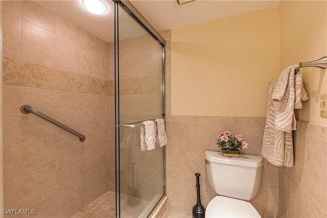 bathroom with a shower with door, toilet, and tile walls