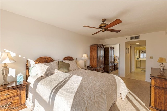 carpeted bedroom with a closet, ensuite bathroom, and ceiling fan