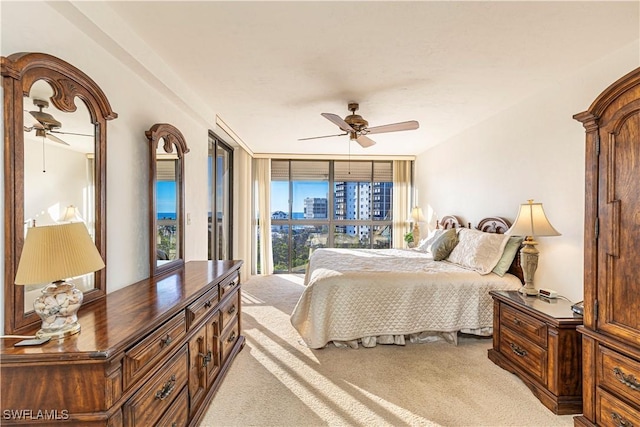 bedroom featuring ceiling fan, light colored carpet, and a wall of windows