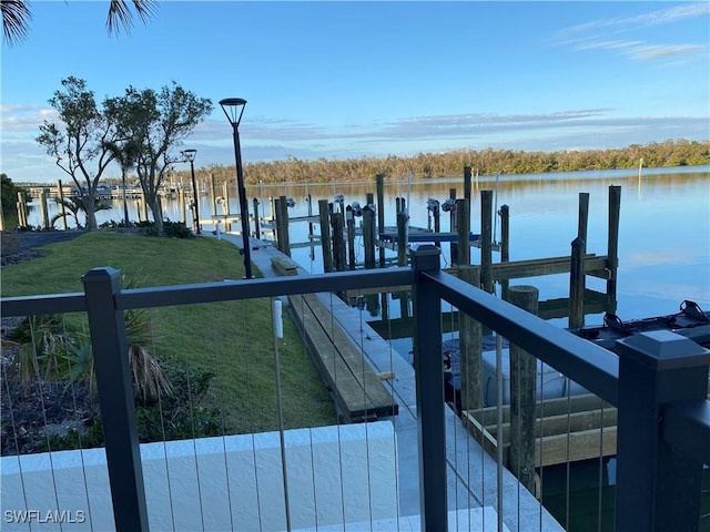 dock area with a lawn and a water view