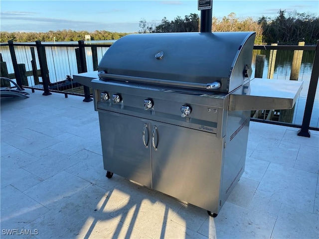 view of patio with a grill and a water view