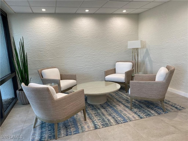 sitting room with a paneled ceiling and light tile patterned flooring