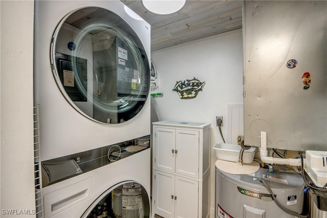 laundry area featuring cabinets, stacked washer / drying machine, and water heater