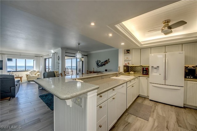 kitchen featuring white cabinetry, ceiling fan, kitchen peninsula, pendant lighting, and white appliances