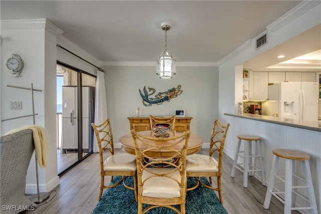 dining space featuring crown molding and light hardwood / wood-style floors